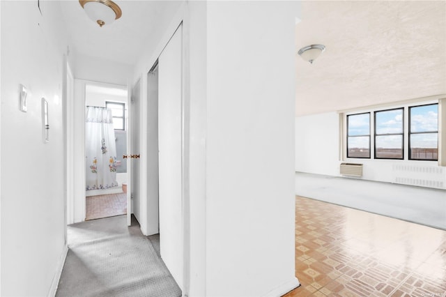 hallway with radiator heating unit, baseboards, and a wall mounted AC