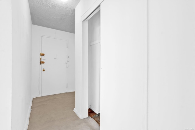 hallway with a textured ceiling and light colored carpet