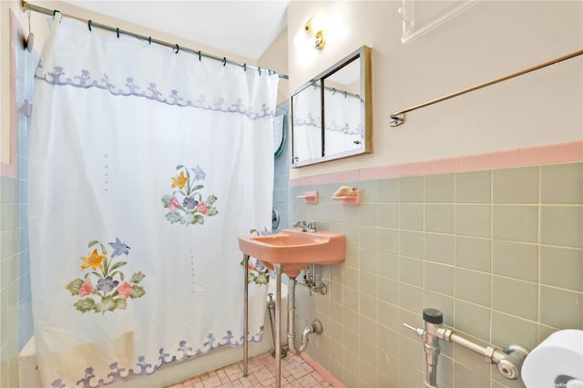 bathroom featuring a sink, a shower with curtain, and tile walls