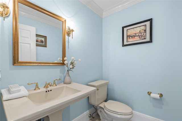 bathroom featuring baseboards, crown molding, toilet, and a sink