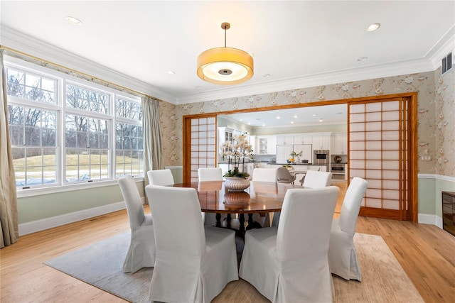 dining space featuring visible vents, crown molding, light wood-style flooring, baseboards, and wallpapered walls