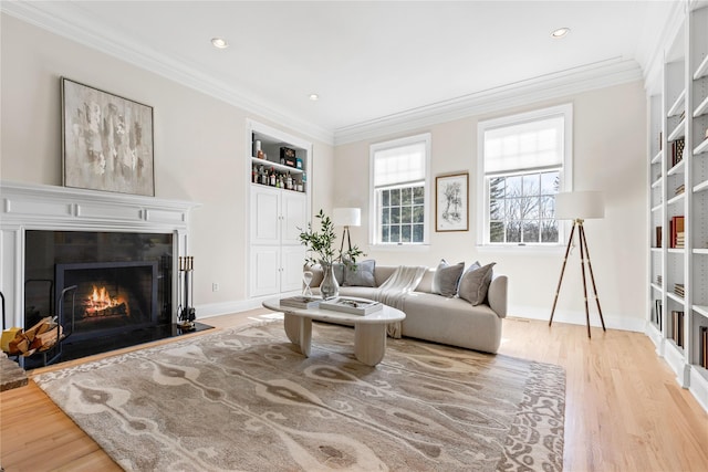living area featuring a fireplace, ornamental molding, built in features, and wood finished floors