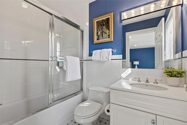 full bathroom featuring tile walls, toilet, bath / shower combo with glass door, and vanity