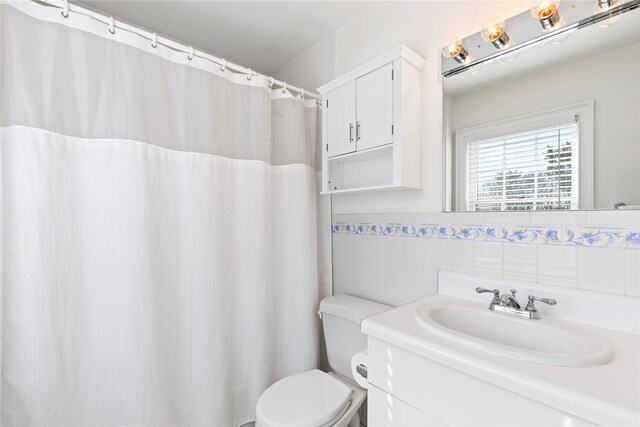 bathroom featuring wainscoting, vanity, tile walls, and toilet