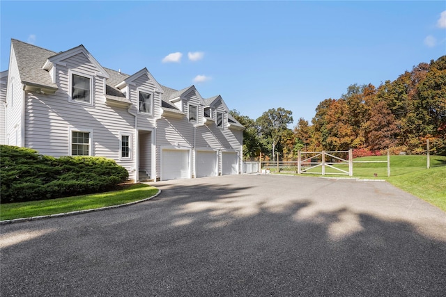 view of home's exterior featuring an attached garage, fence, a lawn, roof with shingles, and driveway