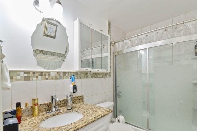 bathroom with toilet, backsplash, vanity, and tile walls