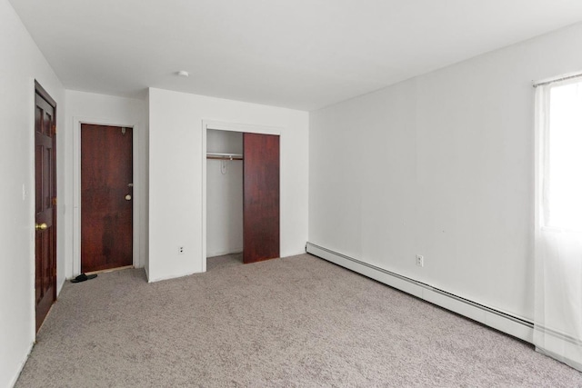 unfurnished bedroom with baseboard heating, a closet, and carpet floors