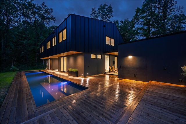 474 Rte 199, Red Hook, NY 12571 - back of house at twilight with board and batten siding, a deck, an outdoor pool, stucco siding, and a patio