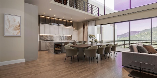 dining area with a high ceiling, beverage cooler, light wood-style flooring, baseboards, and a mountain view