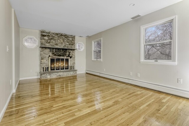 121 Thiells Rd, Stony Point, NY 10980 - unfurnished living room featuring visible vents, wood finished floors, baseboards, a stone fireplace, and baseboard heating