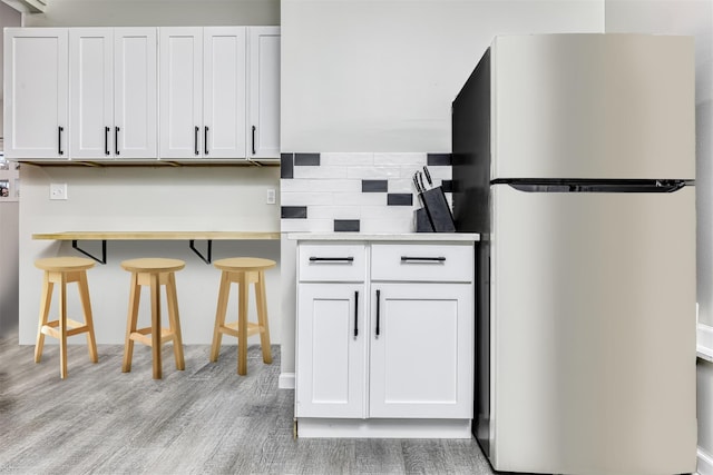 121 Thiells Rd, Stony Point, NY 10980 - kitchen featuring freestanding refrigerator, a kitchen bar, light countertops, light wood finished floors, and backsplash