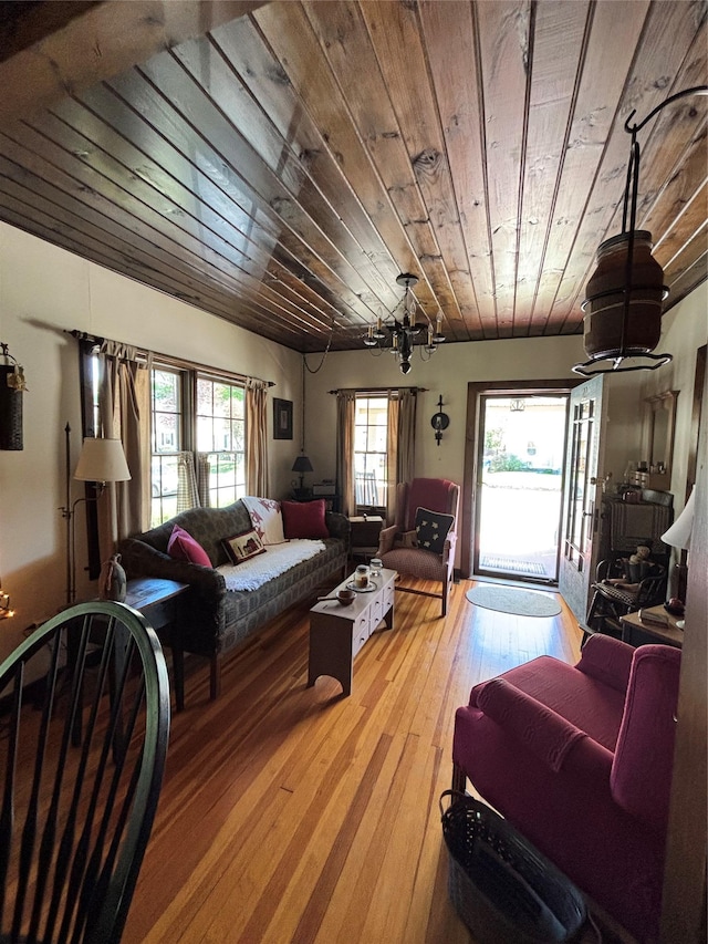 living area with light wood-style floors, a chandelier, and wooden ceiling