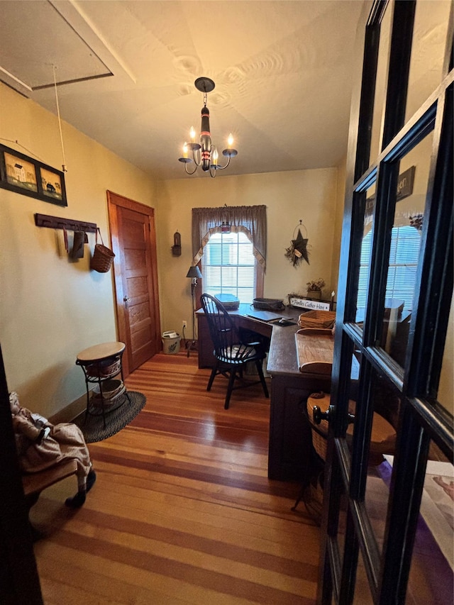 dining area with attic access, wood finished floors, and a notable chandelier