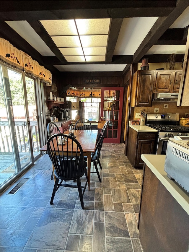dining space with wood walls, visible vents, and stone finish floor