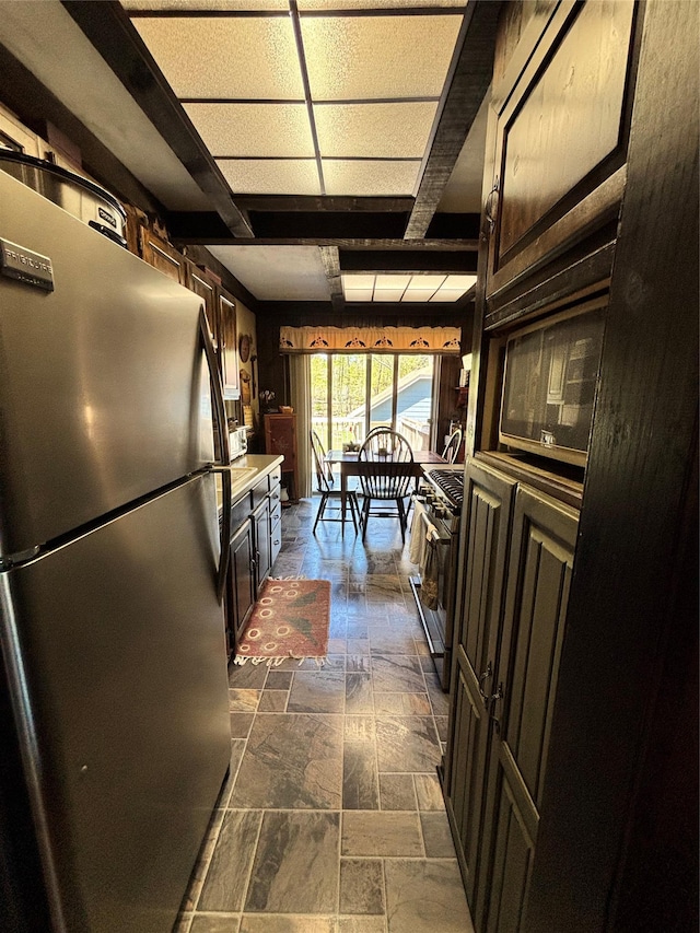 kitchen with stone tile flooring, light countertops, appliances with stainless steel finishes, and dark brown cabinetry