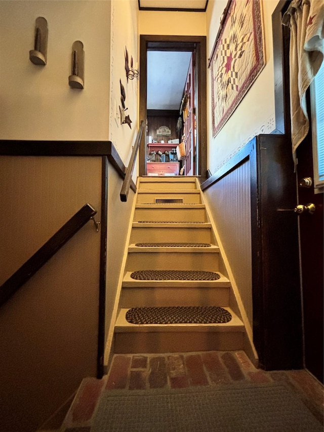 stairs featuring a wainscoted wall