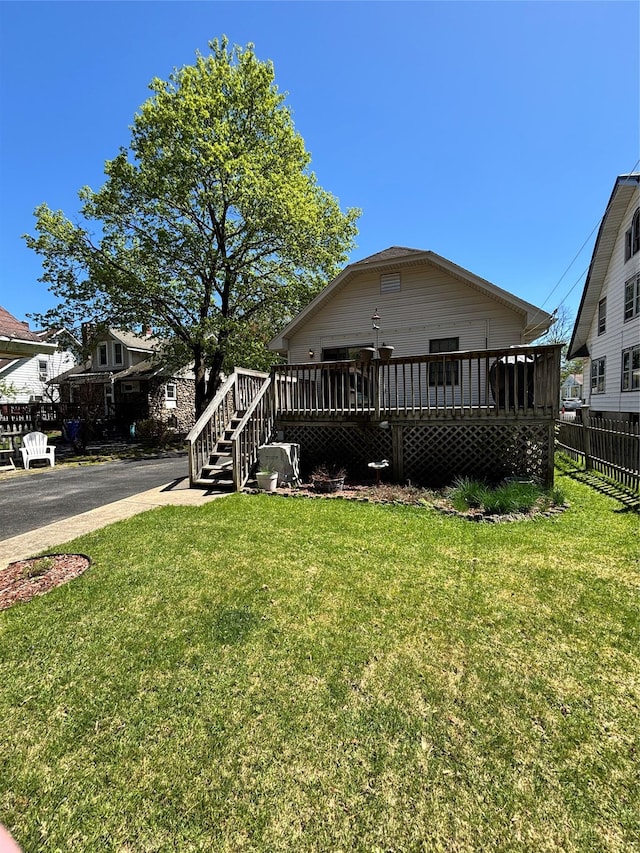view of front facade featuring fence, stairway, a deck, and a front yard