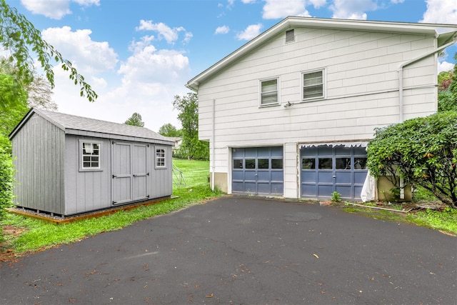 12 Jay Ct, Monsey, NY 10952 - view of side of home with an attached garage, asphalt driveway, an outdoor structure, and a storage shed