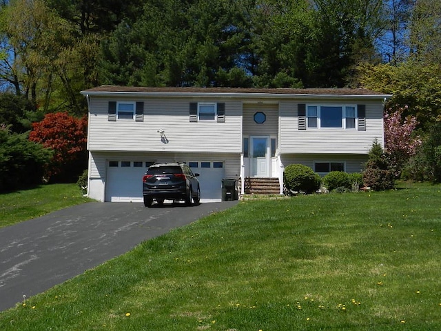 bi-level home with driveway, a front lawn, entry steps, and a garage