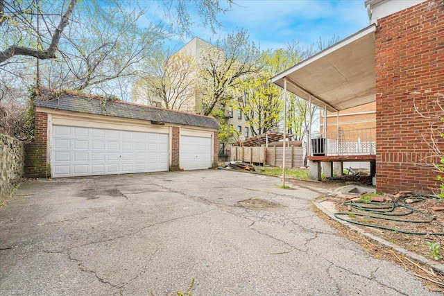detached garage featuring fence and central AC unit