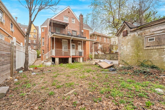 rear view of house with brick siding, fence, a chimney, and a deck