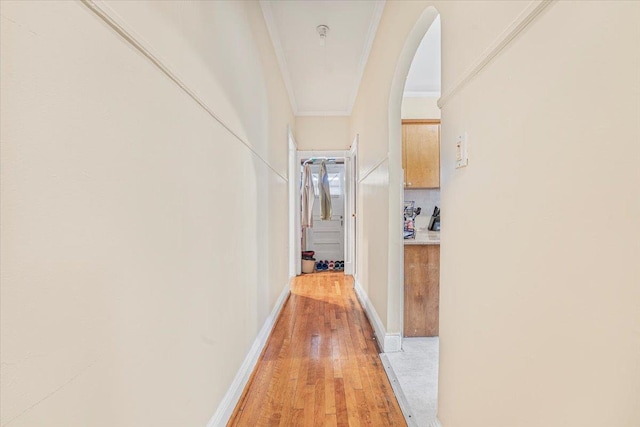 hall featuring crown molding, arched walkways, and light wood finished floors