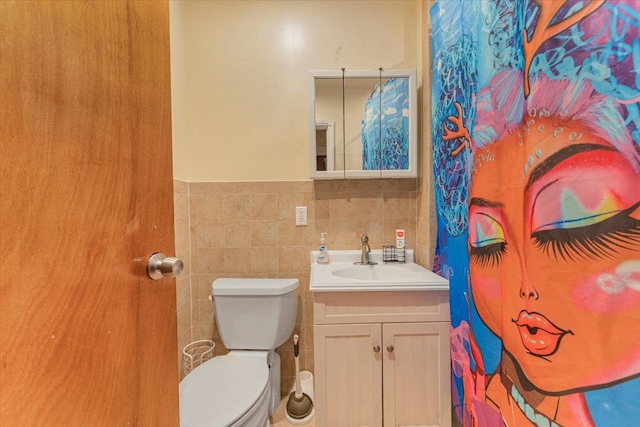 bathroom with toilet, tile walls, and vanity