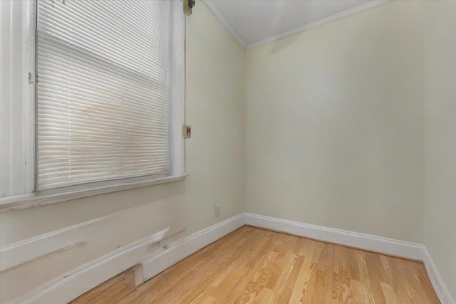 empty room featuring baseboards, ornamental molding, and light wood finished floors