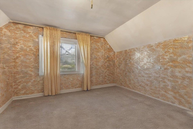 additional living space with baseboards, carpet flooring, wallpapered walls, and lofted ceiling
