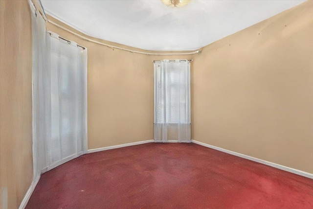 carpeted empty room featuring baseboards