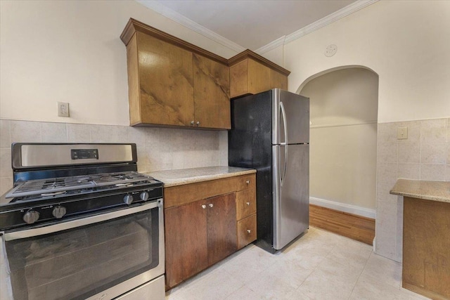 kitchen with crown molding, stainless steel appliances, brown cabinetry, and light tile patterned floors