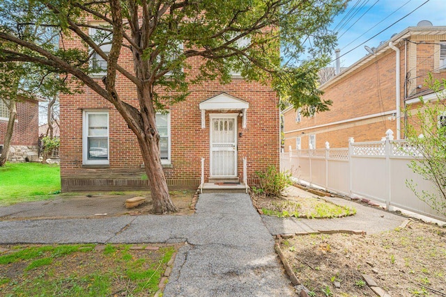 property entrance featuring brick siding and fence