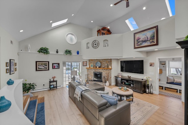 living room with a stone fireplace, high vaulted ceiling, a skylight, and light wood-type flooring