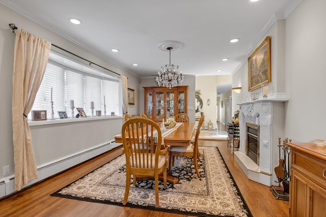 dining area featuring crown molding, a baseboard radiator, light wood-style flooring, and a chandelier