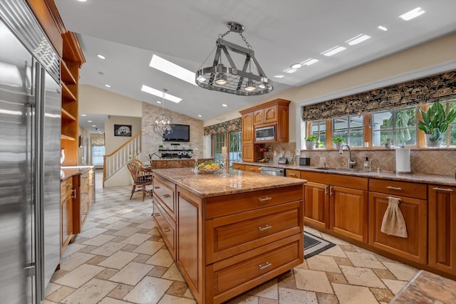 kitchen with backsplash, a sink, lofted ceiling with skylight, a chandelier, and built in appliances