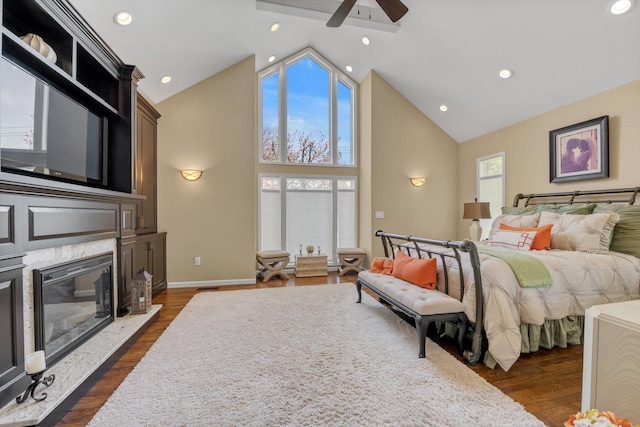 bedroom featuring a ceiling fan, a premium fireplace, high vaulted ceiling, and dark wood-style floors