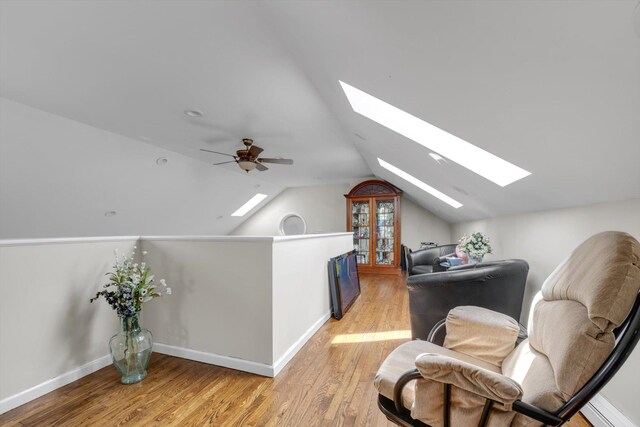 additional living space featuring light wood-type flooring, baseboards, lofted ceiling with skylight, and ceiling fan