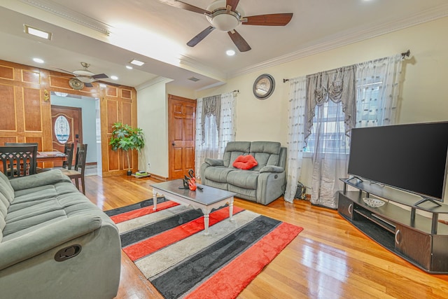 living area with crown molding, ceiling fan, a wealth of natural light, and wood finished floors
