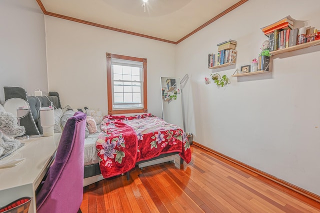 bedroom with crown molding, baseboards, ceiling fan, and hardwood / wood-style floors
