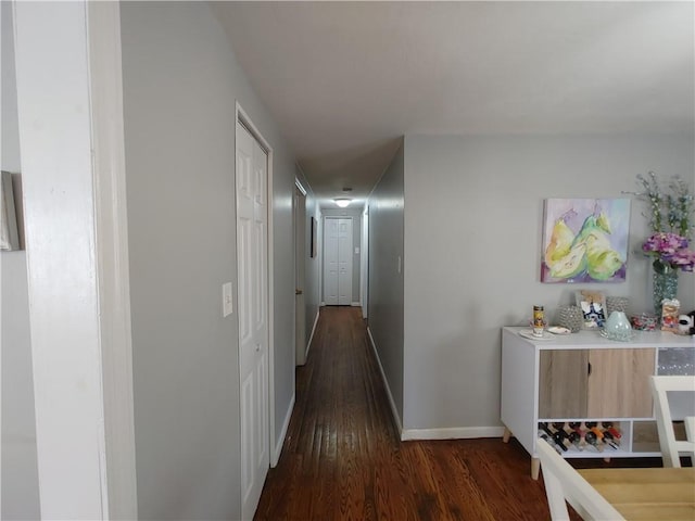 corridor featuring baseboards and dark wood finished floors