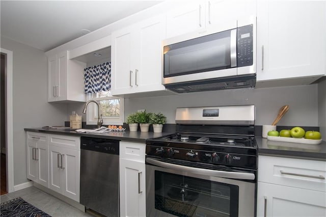 kitchen with a sink, dark countertops, white cabinets, and stainless steel appliances