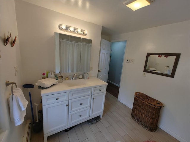 full bath featuring vanity, baseboards, baseboard heating, and wood finished floors