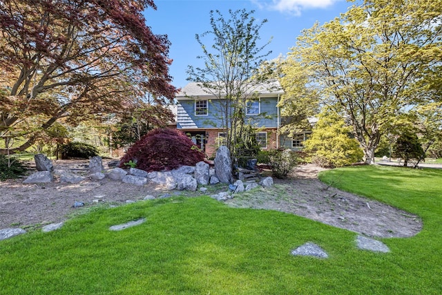 rear view of property featuring a lawn and brick siding