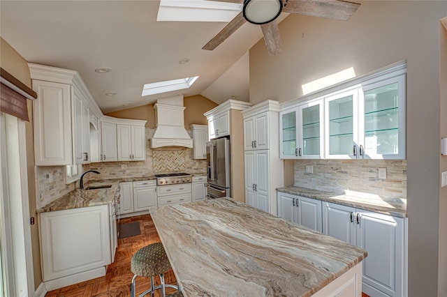 137 Melbury Rd, Babylon, NY 11702 - kitchen with stainless steel appliances, a skylight, premium range hood, decorative backsplash, and lofted ceiling