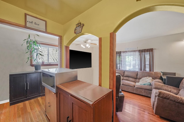 interior space with arched walkways, ceiling fan, and light wood-style flooring