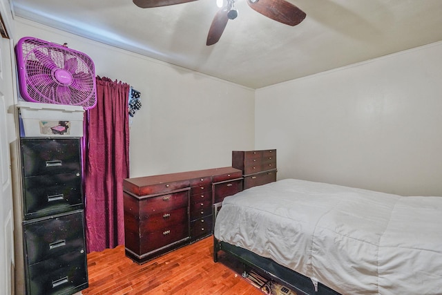 bedroom featuring crown molding, a ceiling fan, and wood finished floors