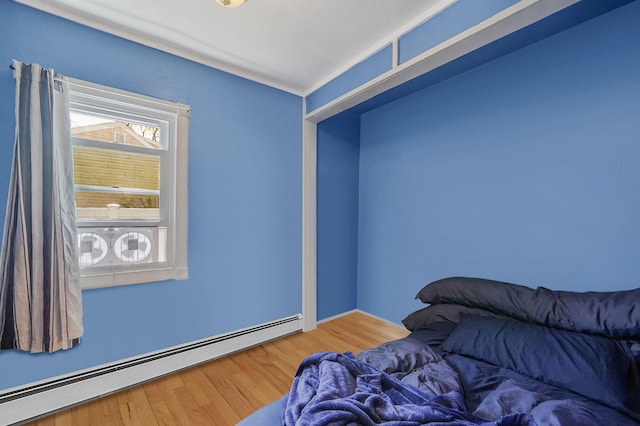 bedroom with a baseboard radiator and wood finished floors