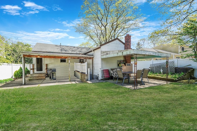 rear view of property featuring a lawn, a fenced backyard, a patio area, and a chimney