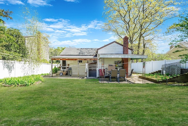 back of property with a fenced backyard, a patio, a chimney, and a yard