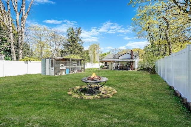 view of yard featuring a fenced backyard, an outbuilding, and an outdoor fire pit